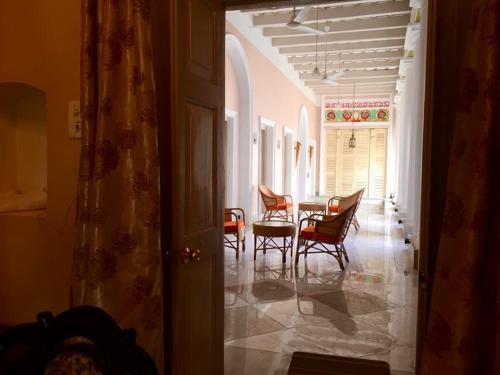a hallway with chairs and a table in a room at COSSIMBAZAR PALACE OF THE ROYS ( RAJBARI) in Cossimbāzār
