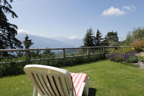 a white chair sitting on a lawn with a view at Hotel-Restaurant Le Mont Paisible, Crans-Montana in Crans-Montana