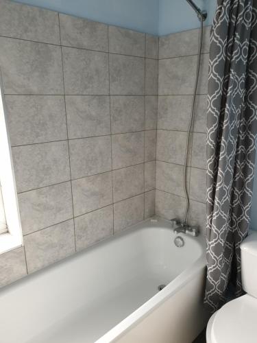 a bathroom with a white tub and a shower curtain at Tower House Hotel in Reading