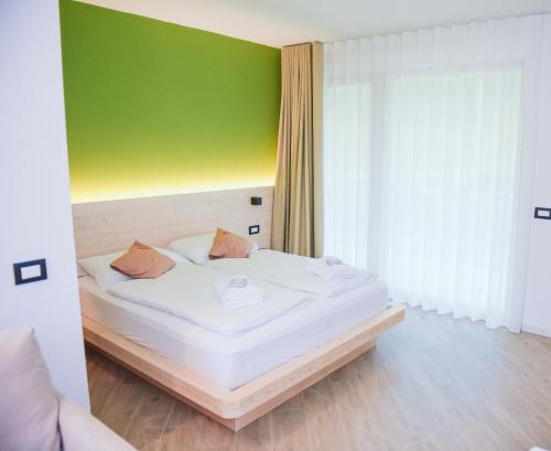 a bedroom with a white bed with a green wall at Agritur Verderame in Trento