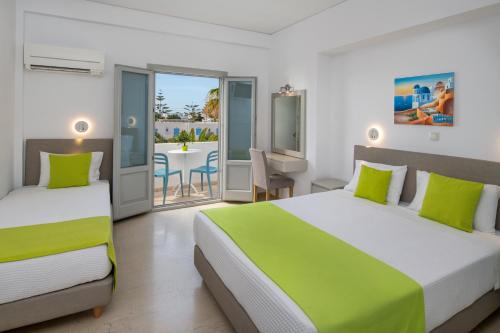 a bedroom with two beds and a balcony with a table at Makarios Hotel in Kamari