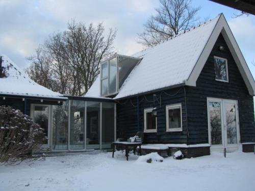 a black house with snow on the roof at Vakantiewoning "De Kei" in Warns