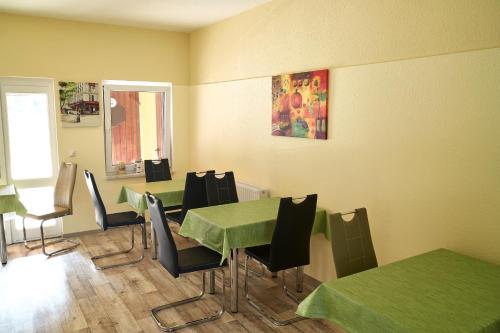 a dining room with green tables and black chairs at Pension Waldbad Dommitzsch in Dommitzsch