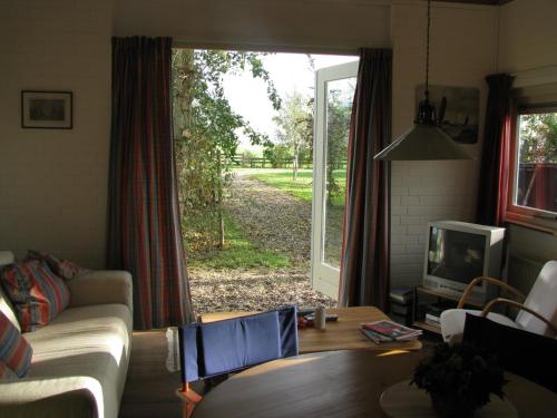 a living room with a couch and a tv and a window at Vakantiewoning "De Kei" in Warns