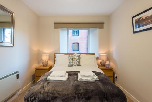 a bedroom with a bed with two lamps and a window at The Maltings in Edinburgh