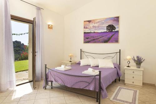 um quarto com uma cama com lençóis roxos e um quadro em Porto Cervo-Villa La Gjanda em Abbiadori