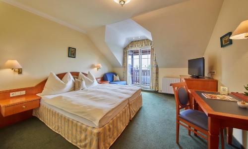 um quarto de hotel com uma cama, uma secretária e uma televisão em Hotel Die Pflegerbrücke em Salzburgo