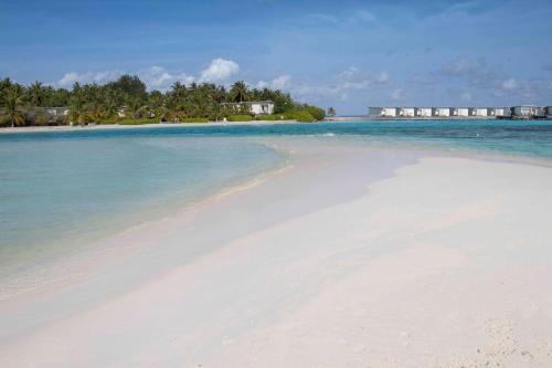 a beach in the ocean with a house in the background at Rosy Villa Hotel in Guraidhoo
