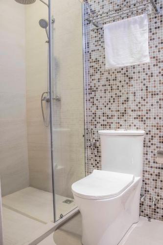 a bathroom with a toilet and a glass shower at Rosy Villa Hotel in Guraidhoo