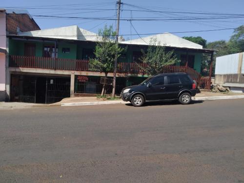 una macchina nera parcheggiata di fronte a un edificio di Hostel el Amanecer a Puerto Iguazú