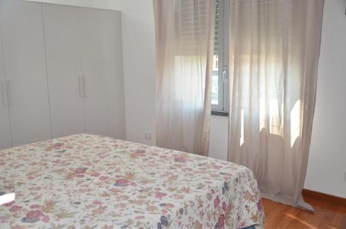 um quarto com uma cama com colcha floral e uma janela em Tuttomondo em Pisa