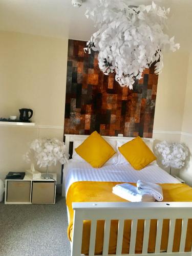 a bedroom with a bed with yellow and white pillows at Waterfront Inn in Shanklin