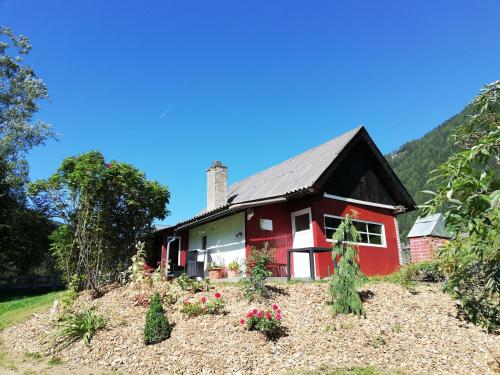 uma casa vermelha numa colina com flores em Almland Hütte em Pusterwald