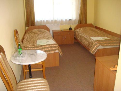 a hotel room with two beds and a table and chairs at Hotel Pod Jaskółką in Zagnańsk