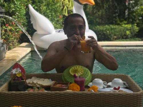 a man sitting in a pool with a tray of food at Ubud Paradise Villa in Ubud