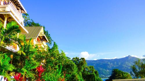 a building with trees and mountains in the background at Mouggae Blues Villas in Beau Vallon
