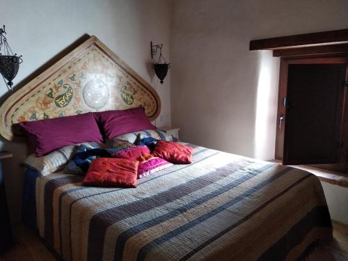 Casa con encanto en Valdelarco في Valdelarco: غرفة نوم مع سرير كبير مع وسائد أرجوانية