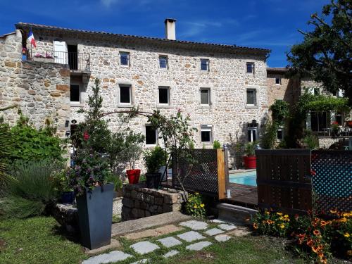 an old stone house with a pool in front of it at La musardière in Les Assions