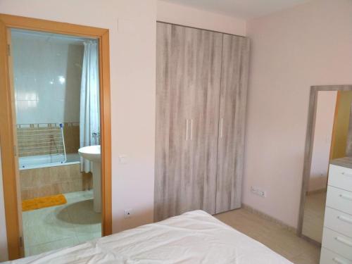 een slaapkamer met een bed en een badkamer met een spiegel bij Apartamento San Carlos de la Rápita in Sant Carles de la Ràpita