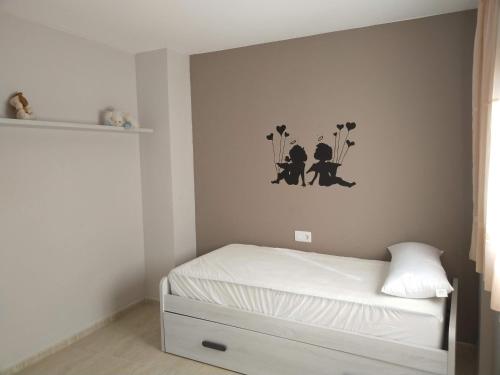 een kleine slaapkamer met een bed en bloemen aan de muur bij Apartamento San Carlos de la Rápita in Sant Carles de la Ràpita