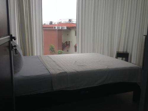 a bed in a room with a large window at Room2Board Hostel and Surf School in Jacó