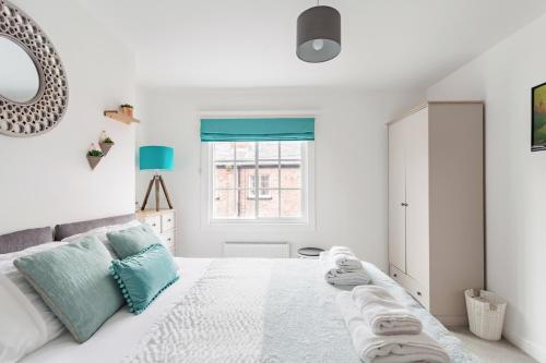 a white bedroom with a large bed with towels on it at Secret City Courtyard Cottage Within Chester City Walls in Chester