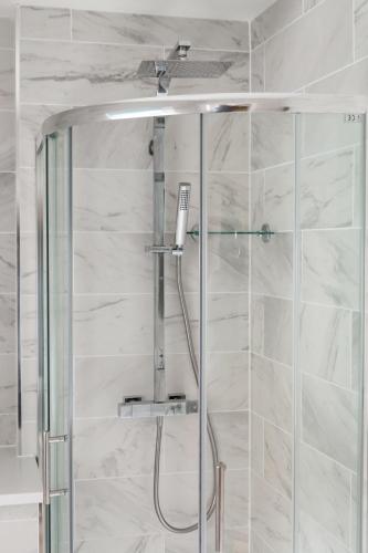 a shower in a bathroom with white marble walls at Secret City Courtyard Cottage Within Chester City Walls in Chester