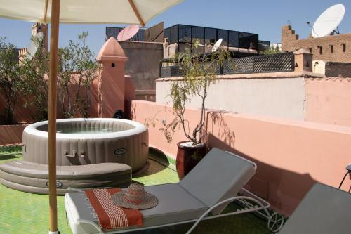 un patio con una silla y una sombrilla en el techo en Riad Orange, en Marrakech