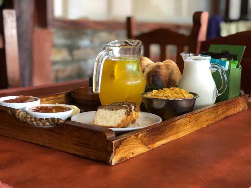 una bandeja de comida en una mesa con zumo de naranja y pan en Cabañas Tierra del Sol Aldea de Montaña en Los Árboles