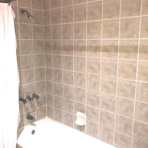 a bathroom with a tiled shower with a white tub at Reef Winds Villa in Runaway Bay