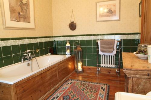een badkamer met een bad en groene betegelde muren bij Badgers Inn in Petworth
