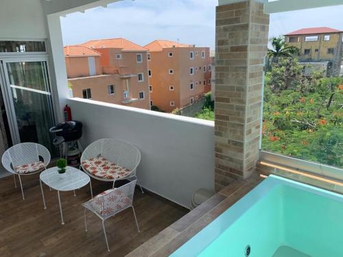 un balcón con piscina, mesas y sillas en KSL Residence en Boca Chica