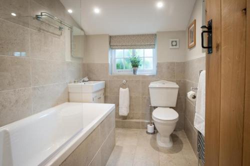 a bathroom with a tub and a toilet and a sink at Westgate Lodge at Dedham in Dedham