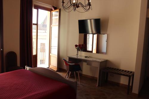 a bedroom with a desk and a bed and a window at Case Vacanze Al Duomo in Licata