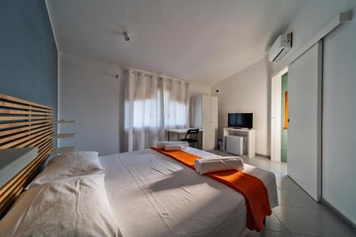 1 dormitorio con 1 cama blanca grande con manta naranja en Chiara’s Home, en Davoli