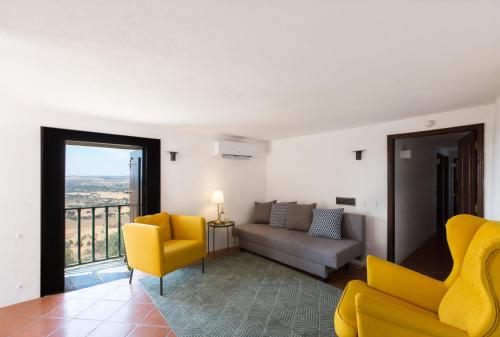 a living room with yellow chairs and a couch at Estalagem de Monsaraz in Monsaraz