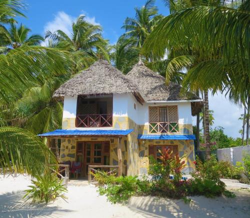 une maison sur la plage avec des palmiers dans l'établissement Santa Maria Coral Park, à Pongwe