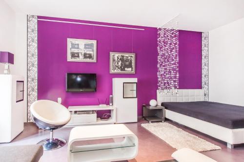 purpurowa sypialnia z łóżkiem i telewizorem w obiekcie Apartment Bubenikova w mieście Pardubice