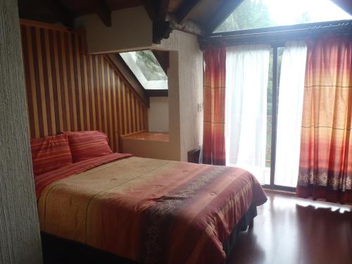 a bedroom with a bed and a window at Cabañas Sierra Verde in Zacatlán