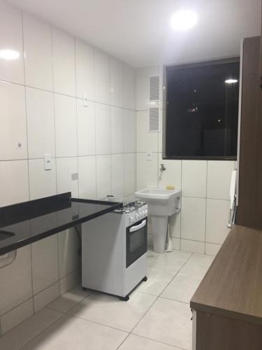 une cuisine blanche avec une cuisinière et un évier dans l'établissement Temporada Arraial do Cabo, à Arraial do Cabo