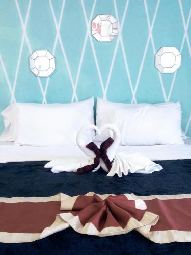 a bedroom with a bed with two swans on it at The Red Hut Inn in Belize City