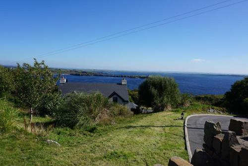 a house on the side of a road next to a body of water at Lighthouse Cottage in Donegal