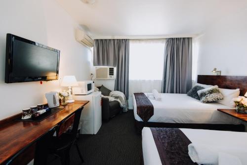 a hotel room with a bed and a desk at Tamworth City Motel in Tamworth