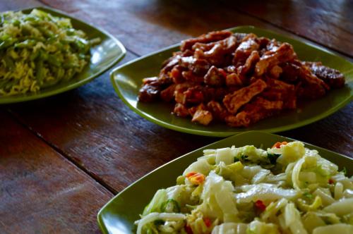 three plates of food on a wooden table at Pristine Paradise Dive Resort - Togean Islands, Una Una in Pulau Unauna