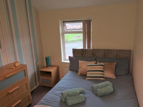 a bedroom with a bed with two pillows and a window at Fearnhead House in Warrington