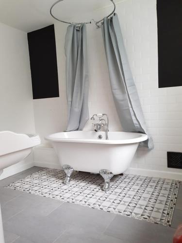 a white bath tub in a bathroom with a sink at Brecon Burrows in Dowlais