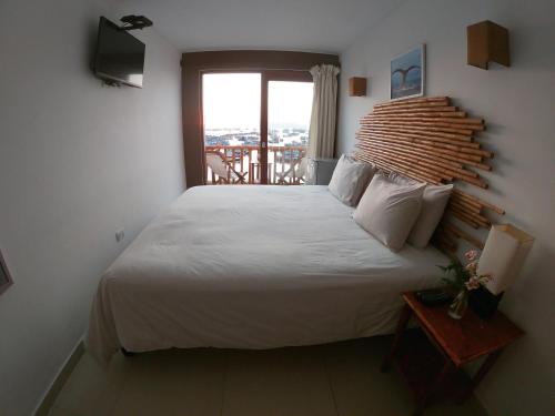 a bedroom with a large bed and a balcony at Bamboo Lodge Paracas in Paracas