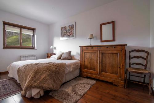 a bedroom with a bed and a wooden dresser and a chair at NOGUERA de Alma de Nieve in Baqueira-Beret