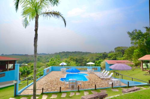 a resort with a pool and a palm tree at Pousada Recanto dos Maximianos in Jarinu