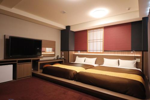 una camera con 2 letti e una TV a schermo piatto di Urbain Kyoto Kiyomizugojo a Kyoto